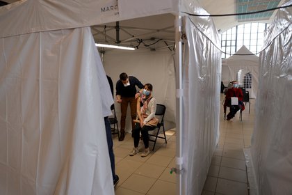 Una mujer, con una mascarilla protectora, recibe una dosis de la vacuna Moderna COVID-19 en un centro de vacunación en Marcq-en-Baroeul como parte de la campaña de vacunación contra la enfermedad por coronavirus en Francia (Reuters)