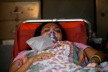 Una paciente con un problema respiratorio usa una máscara de oxígeno mientras yace dentro de una ambulancia esperando en una fila para ingresar a un hospital COVID-19, en medio de la pandemia de la enfermedad por coronavirus, Ahmedabad, India, 14 de abril de 2021. REUTERS / Amit Dave