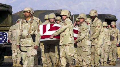 Los soldados estadounidenses llevan los restos envueltos en banderas de la tripulación de un helicóptero durante una ceremonia en la base aérea de Bagram, el 25 de marzo de 2003, en Afganistán. (FOTO AFP / SHAH MARAI)