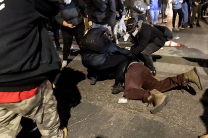 Un manifestante es ayudado por otros después de ser herido por una bomba de gas lacrimógeno frente a la estación de policía de Brooklyn Center mientras la gente se reúne para protestar después de que un oficial de policía disparó y mató a un hombre negro en Brooklyn Center, Minneapolis, Minnesota el 11 de abril de 2021. (Photo by Kerem Yucel / AFP)
