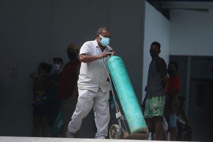 Un trabajador lleva un tanque de oxígeno al interior de un hospital público, durante la pandemia de COVID-19, en la ciudad de Duque de Caxias en el estado de Río de Janeiro, Brasil, 30 de marzo de 2021. REUTERS/Pilar Olivares