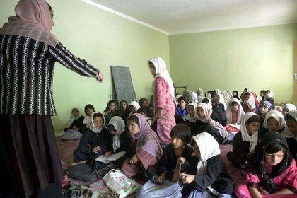 Niñas afganas estudian sentadas en el suelo en una escuela en Kabul, 27 de agosto de 2002. (AFP PHOTO / Deshakalyan CHOWDHURY)