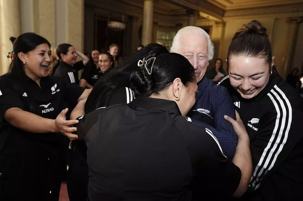 El rey Carlos III recibe un abrazo grupal del equipo de rugby femenil Black Ferns de Nueva Zelanda