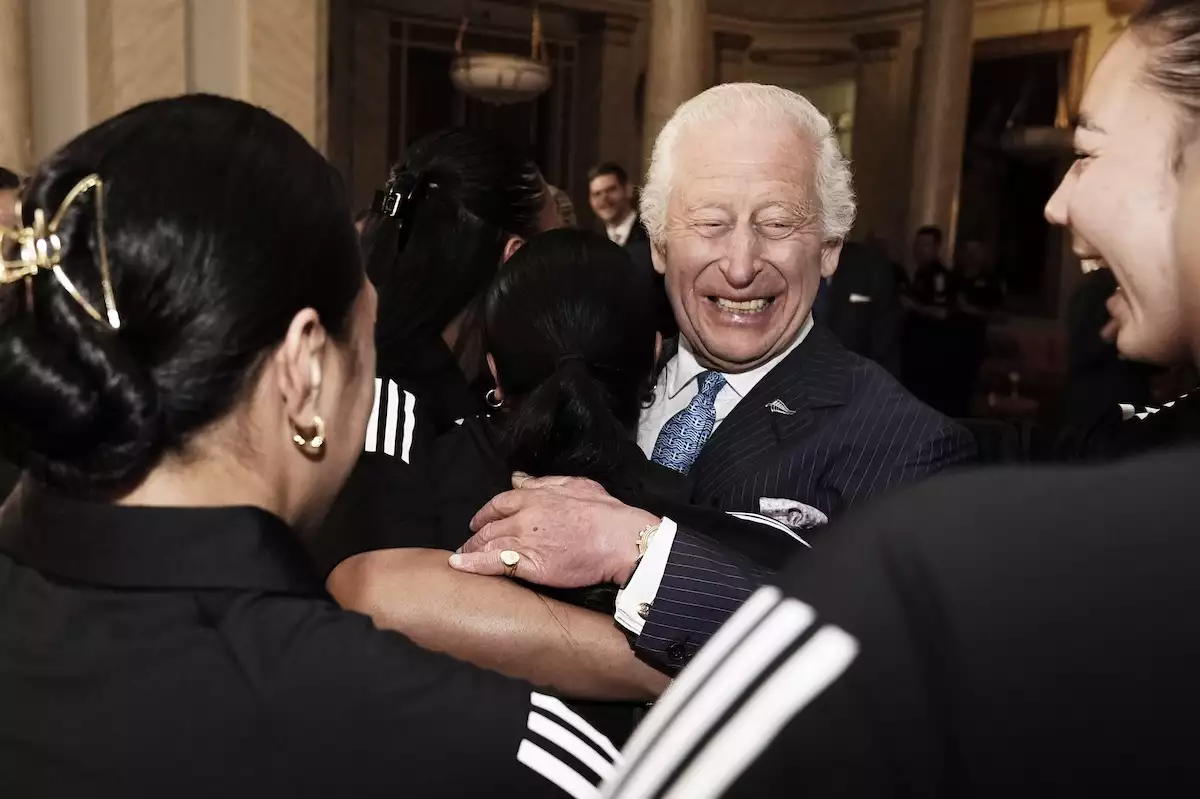 El rey Carlos III recibe un abrazo grupal del equipo de rugby femenil Black Ferns de Nueva Zelanda